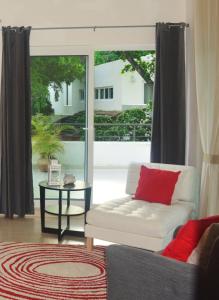 a living room with a white couch and a red pillow at Infiniti Blu Luxury Ocean Front Condos in Sosúa +196 photos