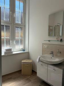 a white bathroom with a sink and two windows at Ferienwohnung Franka in Sonneberg