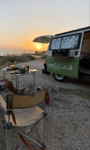 a green van parked on the beach with a table and chairs at Campervan's Algarve in Albufeira
