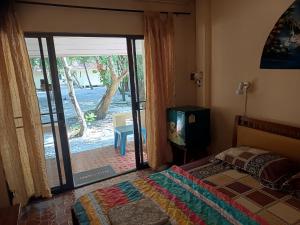 a bedroom with a bed and a tv and a sliding glass door at Buffalo Bay Vacation Club in Ko Phayam +30 photos