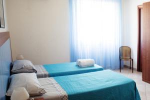 a bedroom with two beds and a chair and a window at A'Luara in San Roberto