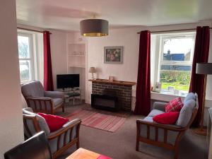 a living room with a fireplace and red curtains at Lochead Cottage Ellary in Lochgilphead