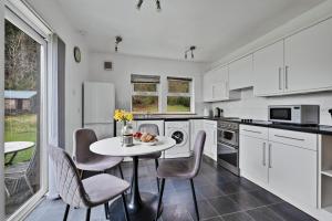 a kitchen with white cabinets and a table and chairs at Lochead Cottage Ellary in Lochgilphead