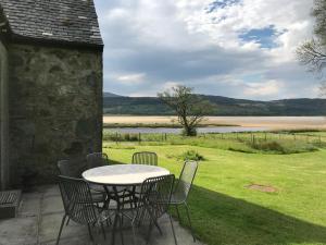 a table and chairs on a patio with a view of a lake at Lochead Cottage Ellary in Lochgilphead