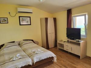a bedroom with a bed and a flat screen tv at Гледката in Mŭdren