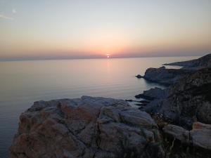 a sunset over the water with rocks in the foreground at Studio centre de calvi in Calvi