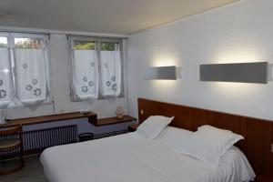 a bedroom with a white bed and two windows at Hôtel le Relais in Eu