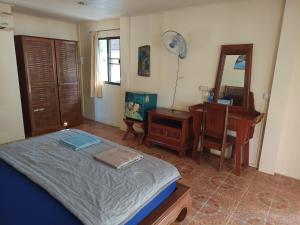 a bedroom with a bed and a desk and a mirror at Buffalo Bay Vacation Club in Ko Phayam