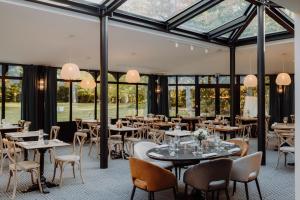 a restaurant with tables and chairs and windows at Les Demeures de Varennes, BW Signature Collection in Varennes-Jarcy