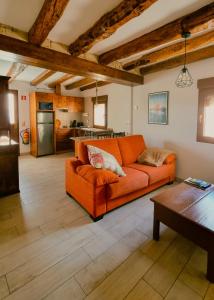 a living room with an orange couch and a kitchen at CASA PESCA VERA in Senegüé