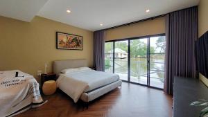 a bedroom with a bed and a sliding glass door at LK Resort in Ban Map Khao Wan
