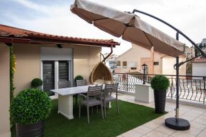 a patio with a table and chairs and an umbrella at Cocoon Urban Suites in Kavála