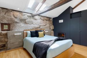 a bedroom with a stone wall and a bed at Casa do Moinho in Aboim