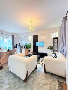 a living room with two white couches and a kitchen at The best west residence in Ruaka