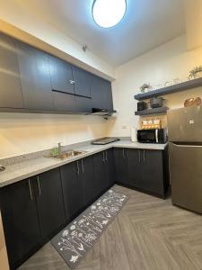 a kitchen with black cabinets and a stainless steel refrigerator at D Grey Pillows - 16th Floor One-Bedroom Condo Unit with Sea View in Pontud +51 photos