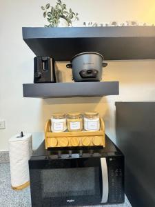 a microwave with three jars on top of it at D Grey Pillows - 16th Floor One-Bedroom Condo Unit with Sea View in Pontud