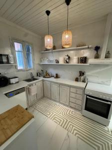 a kitchen with white counters and white cabinets and lights at Blau Haus Townhouse in Lefkada