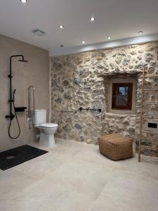 a bathroom with a toilet and a stone wall at Casa Tramuntana in El Port de la Selva +22 photos