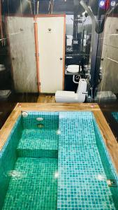a swimming pool with green tiles in a bathroom at The Ocean Crown in Udupi