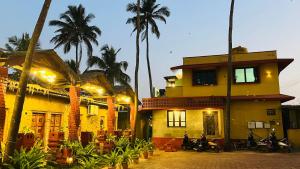 a yellow building with palm trees in front of it at The Ocean Crown in Udupi