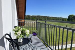 a balcony with two chairs and a table with flowers at Green Hill Domyslow, 6 persons in Kołczewo