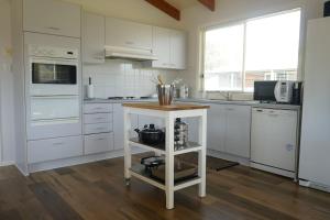 a kitchen with white cabinets and a island in the middle at Mudita at Bonnie Doon in Bonnie Doon