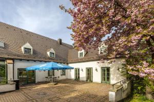 a white building with a blue umbrella in the courtyard at Hotel Holledau in Geisenhausen