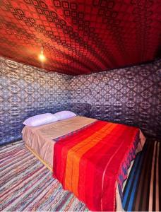 a bedroom with a bed with a colorful blanket at Moon Dunes camp in Adrouine