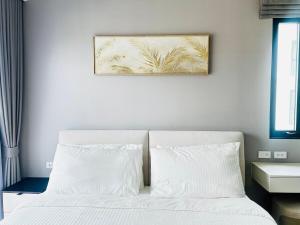 a bed with white pillows and a picture on the wall at Legendary 2 Bdr Comfort in Bang Tao Beach +39 photos