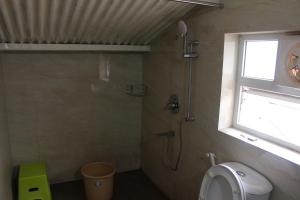 a bathroom with a shower with a toilet and a window at The Attic at Infinity Valley in Kotagiri +2 photos