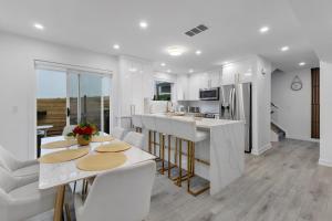 a white kitchen with white counter tops and tables at Guest House in Calgary Downtown in Calgary
