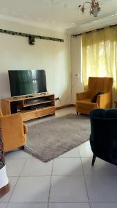 a living room with a flat screen tv and two chairs at Malaika Villas in Kampala
