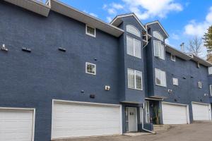 a blue building with three garages and two white garage doors at Guest House in Calgary Downtown in Calgary