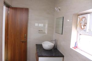 a bathroom with a sink and a wooden door at The Attic at Infinity Valley in Kotagiri