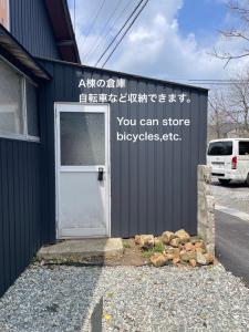a building with a door with a sign on it at コハクサカイミナト in Sakaiminato