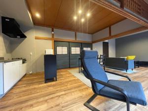 a living room with a blue chair and a couch at コハクサカイミナト in Sakaiminato