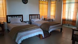 two beds sitting in a room with windows at Moner Pukur in Bolpur