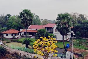a house with palm trees and a yard with yellow flowers at Moner Pukur in Bolpur