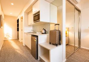 a small kitchen with white cabinets and a suitcase at Newly Restyled Resort Studio Oaks Pacific Blue in Salamander Bay