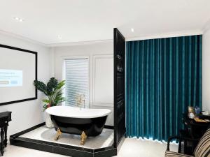 a bathroom with a tub and a green shower curtain at Love Luxury Hotel Bà Điểm in Ho Chi Minh City