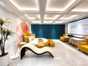 a living room with yellow furniture and a large screen at Love Luxury Hotel Bà Điểm in Ho Chi Minh City
