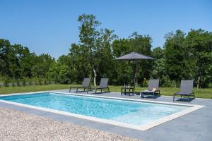 a swimming pool with four chairs and an umbrella at Villa Vivento in Vozilići