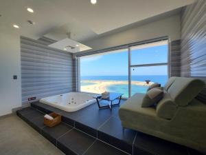 a large living room with a tub and a couch at Sokcho 828 Spa Pension in Sokcho +23 photos