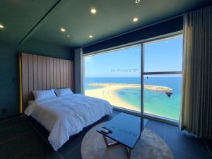 a bedroom with a bed and a view of the beach at Sokcho 828 Spa Pension in Sokcho