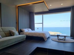 a bedroom with a bed and a couch and a large window at Sokcho 828 Spa Pension in Sokcho