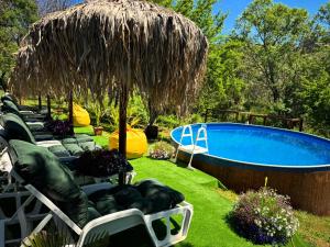 a resort with a swimming pool and a straw umbrella at Къща за гости Дени in Chukovezer