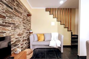 a living room with a couch and a brick wall at Férias na Serra # Natureza # Casa da Professora By ALzira in Seia