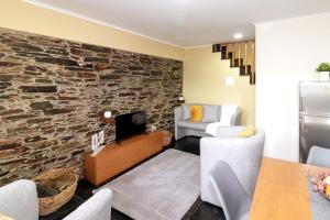 a living room with a stone wall at Férias na Serra # Natureza # Casa da Professora By ALzira in Seia