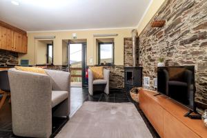 a living room with two chairs and a stone wall at Férias na Serra # Natureza # Casa da Professora By ALzira in Seia
