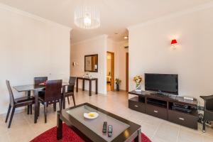 a living room with a television and a dining room at Vandalou By ALzira in Albufeira